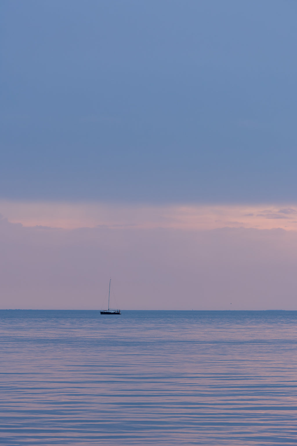 Sunset over the waterfront in Trieste, Italy, reflected in calm water.