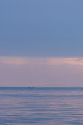 Sunset over the waterfront in Trieste, Italy, reflected in calm water.